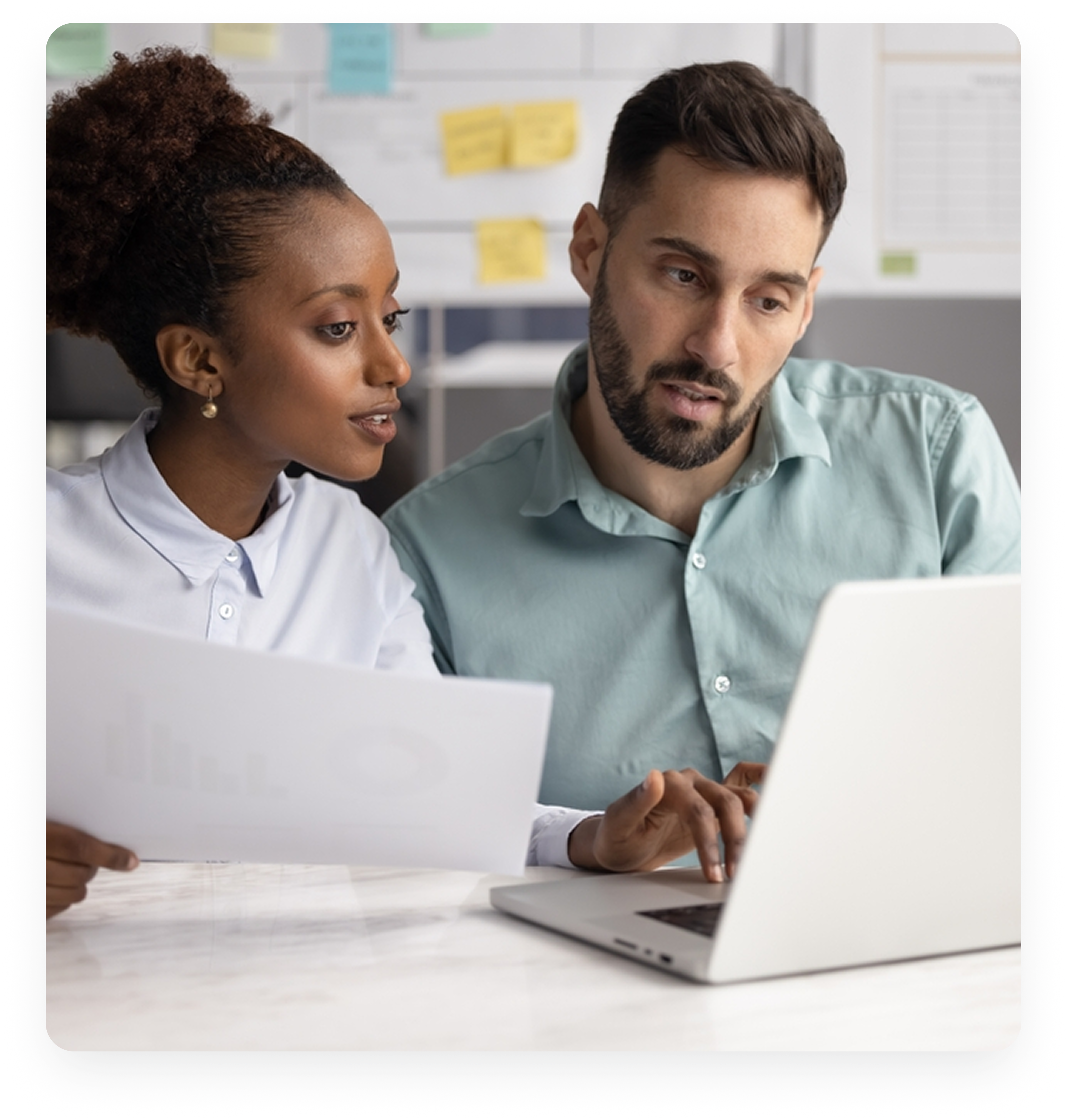Two professionals collaborating while looking at a laptop in an office